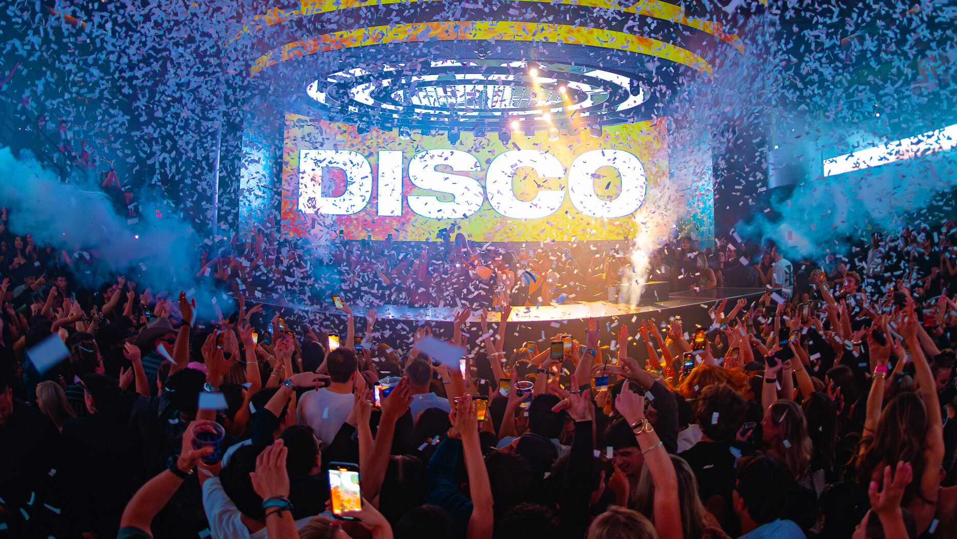 Disco lines surrounded by confetti behind the DJ booth, with the LED stage background displaying "DISCO".