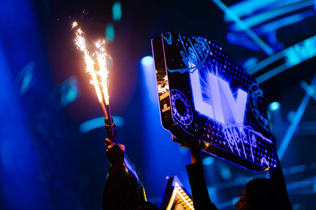 Server hands hold a bottle presentation and Blue Marquee sign that reads, "LIV"