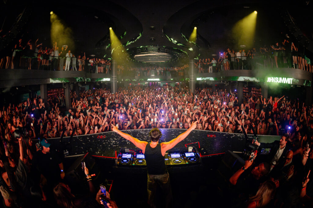 John Summit with his arms extended facing a full crowd.