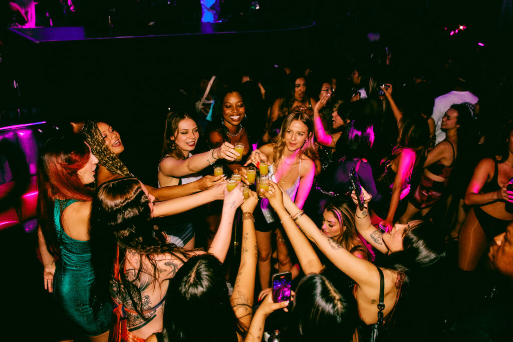 A group of girls cheers a round of drinks.