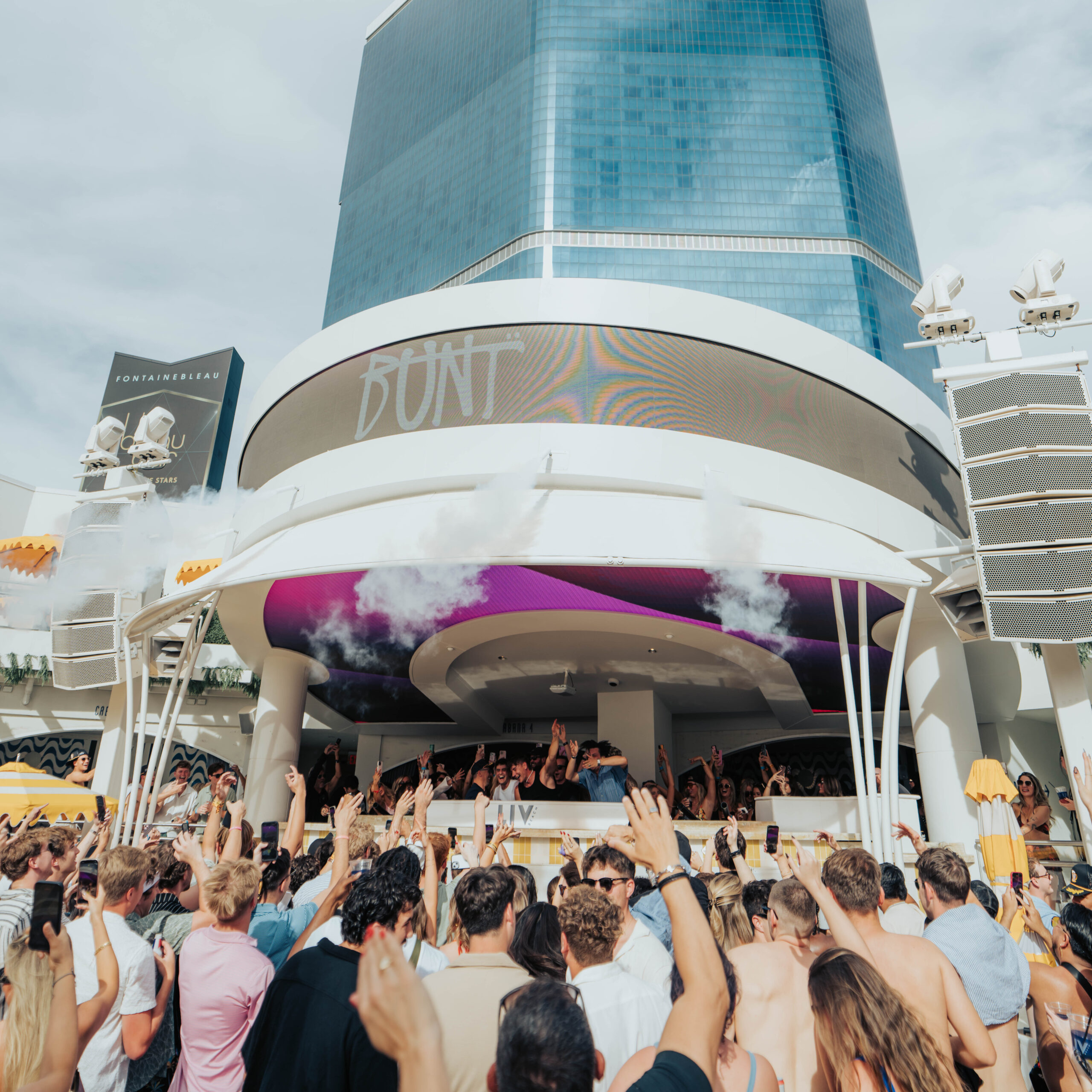 The crowd dancing in front of the DJ Booth, with the LED banner displaying "BUNT"