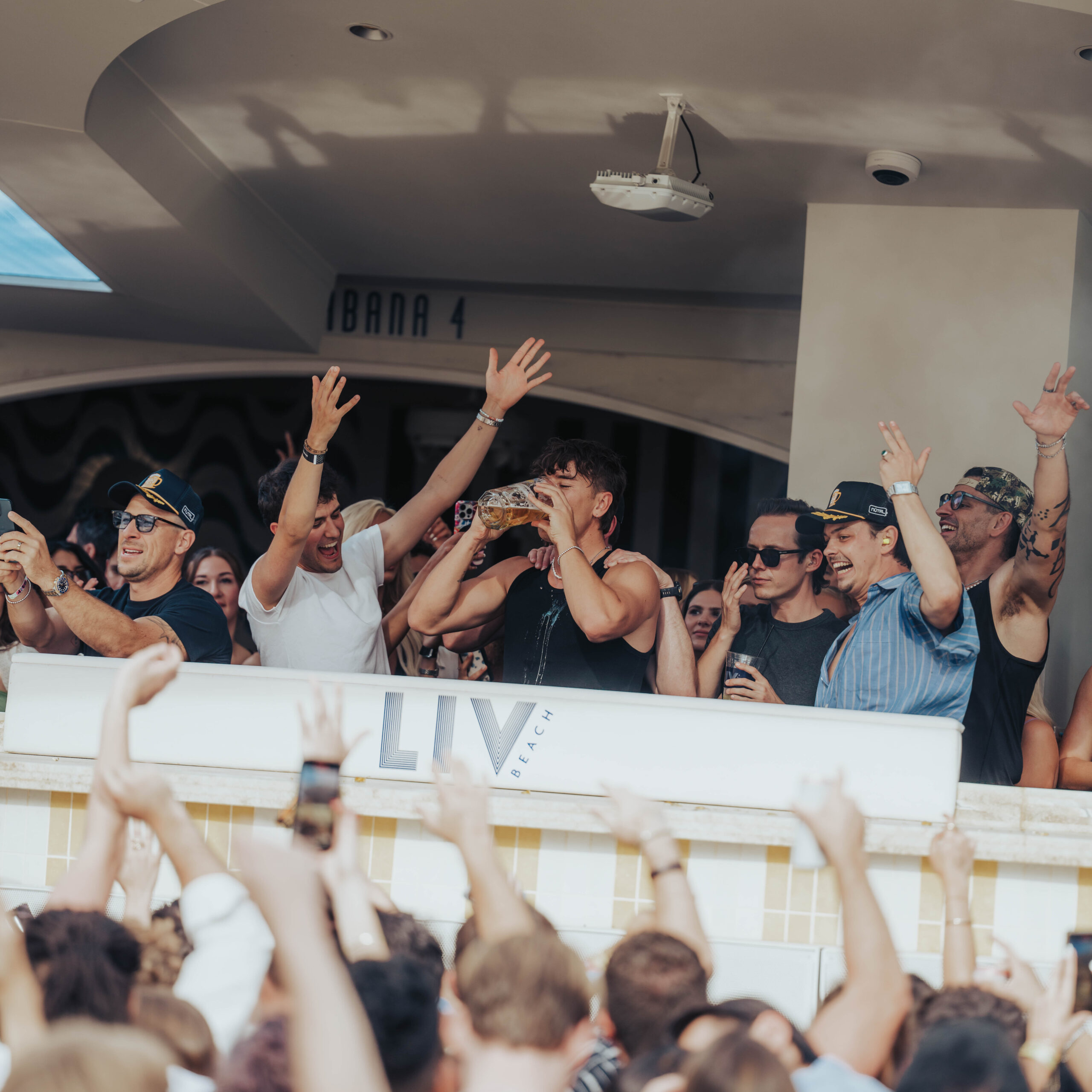 BUNT drinking from a beer stein behind the DJ booth, with the crowd cheering.