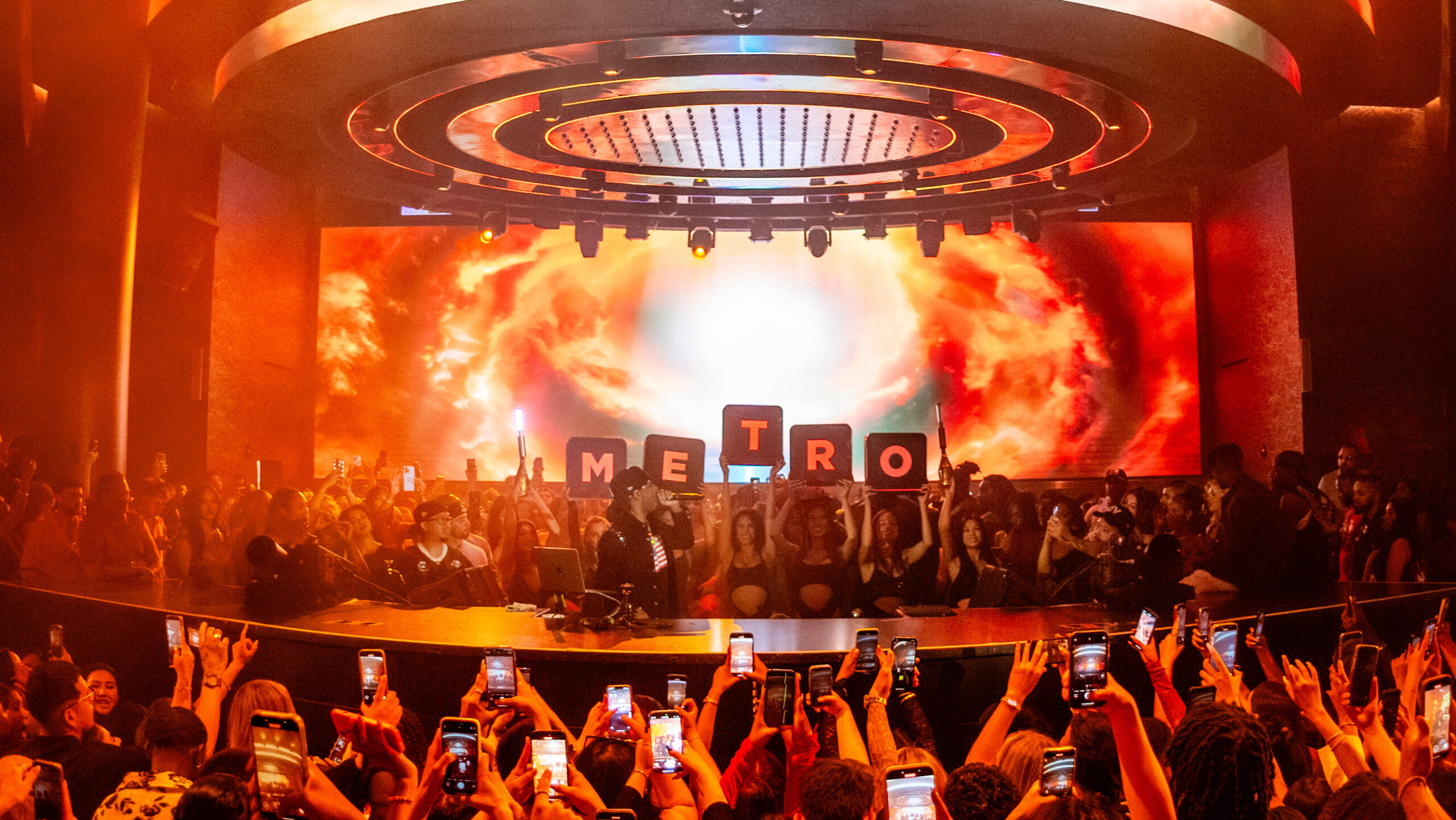 Metro Boomin speaking into the microphone, in front of LED Letterboards that spell out "METRO".