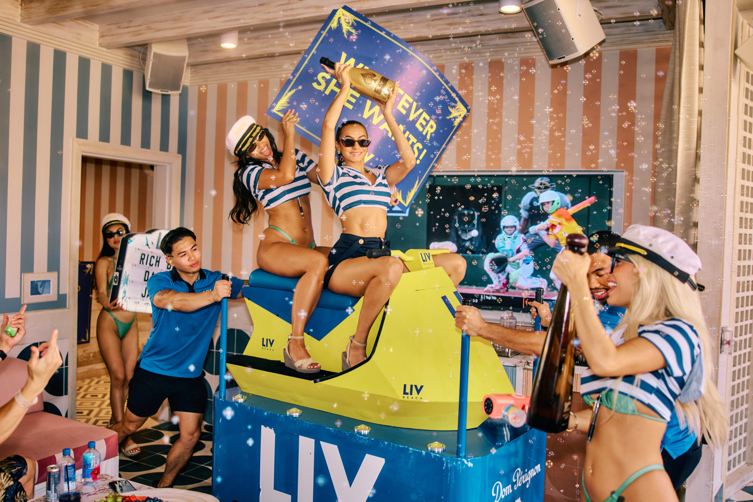 Bottle servers holding champagne and marquee signs surrounded by bubbles.