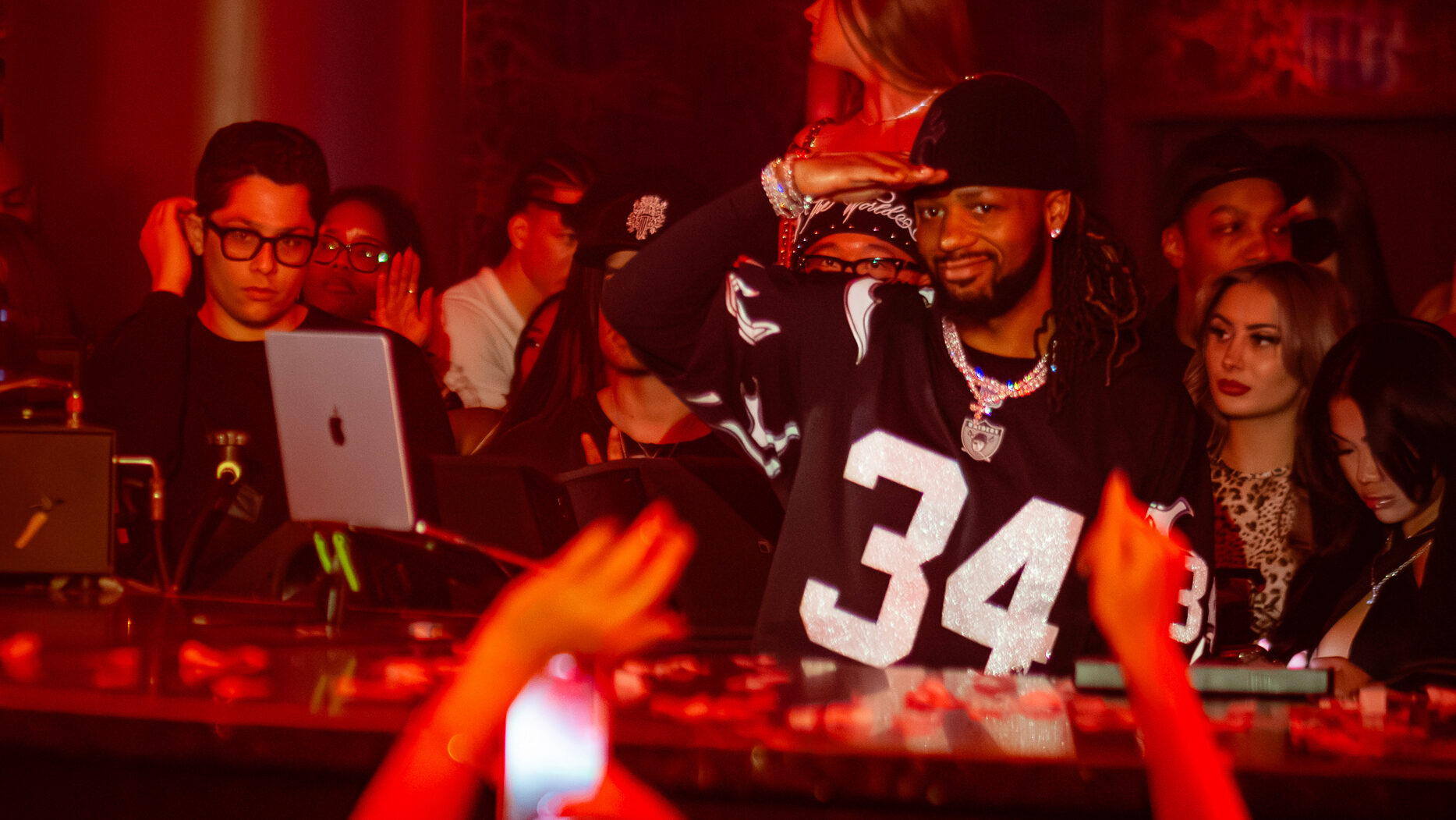 Metro Boomin salutes crowd while DJing at LIV Las Vegas under red nightclub lighting.