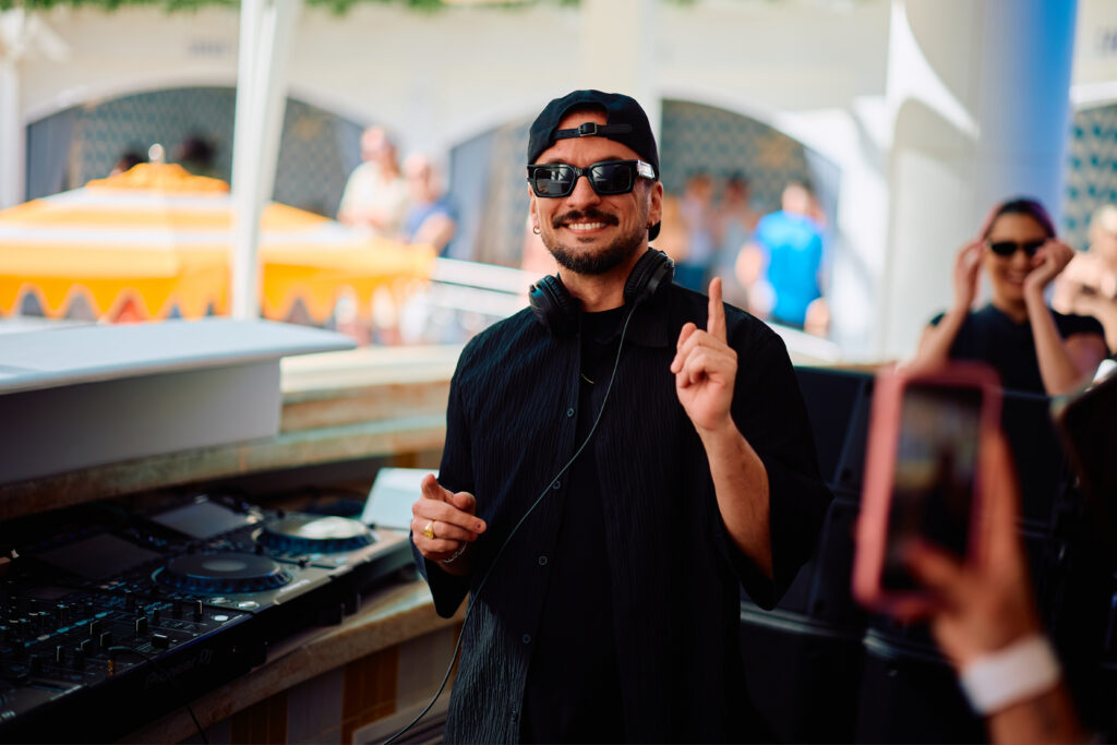 Dombresky performing at LIV Beach poolside DJ booth with crowd and sunglasses.