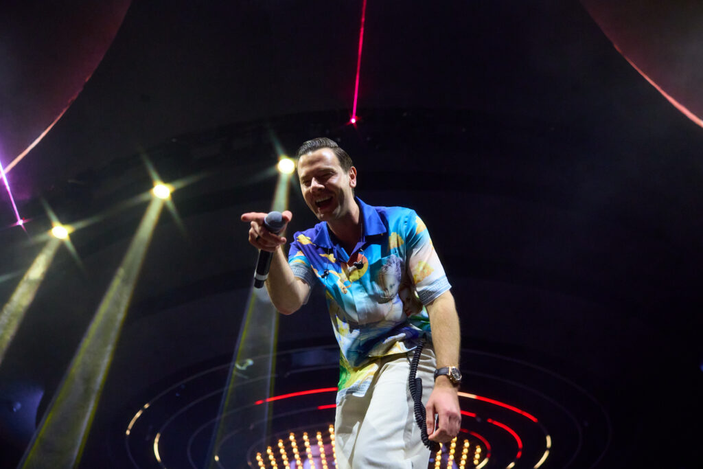 Sam Feldt performing live at LIV Las Vegas, pointing microphone toward crowd under stage lights.