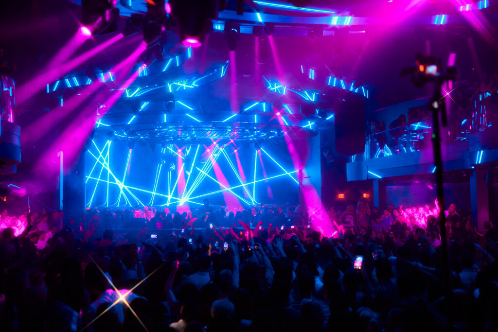 Packed LIV Las Vegas nightclub with neon lights and crowd dancing under vibrant production visuals.