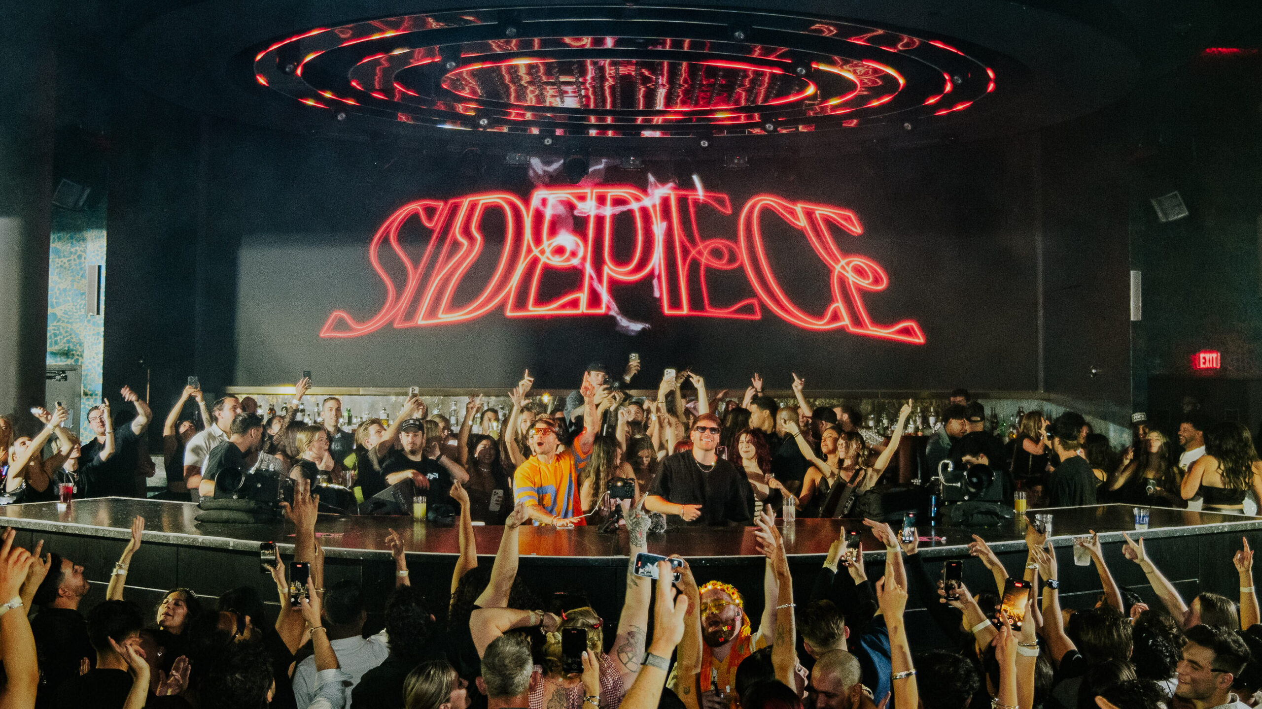 Sidepiece performing at LIV Las Vegas with crowd packed around the DJ booth and LED visuals displaying "Sidepiece".