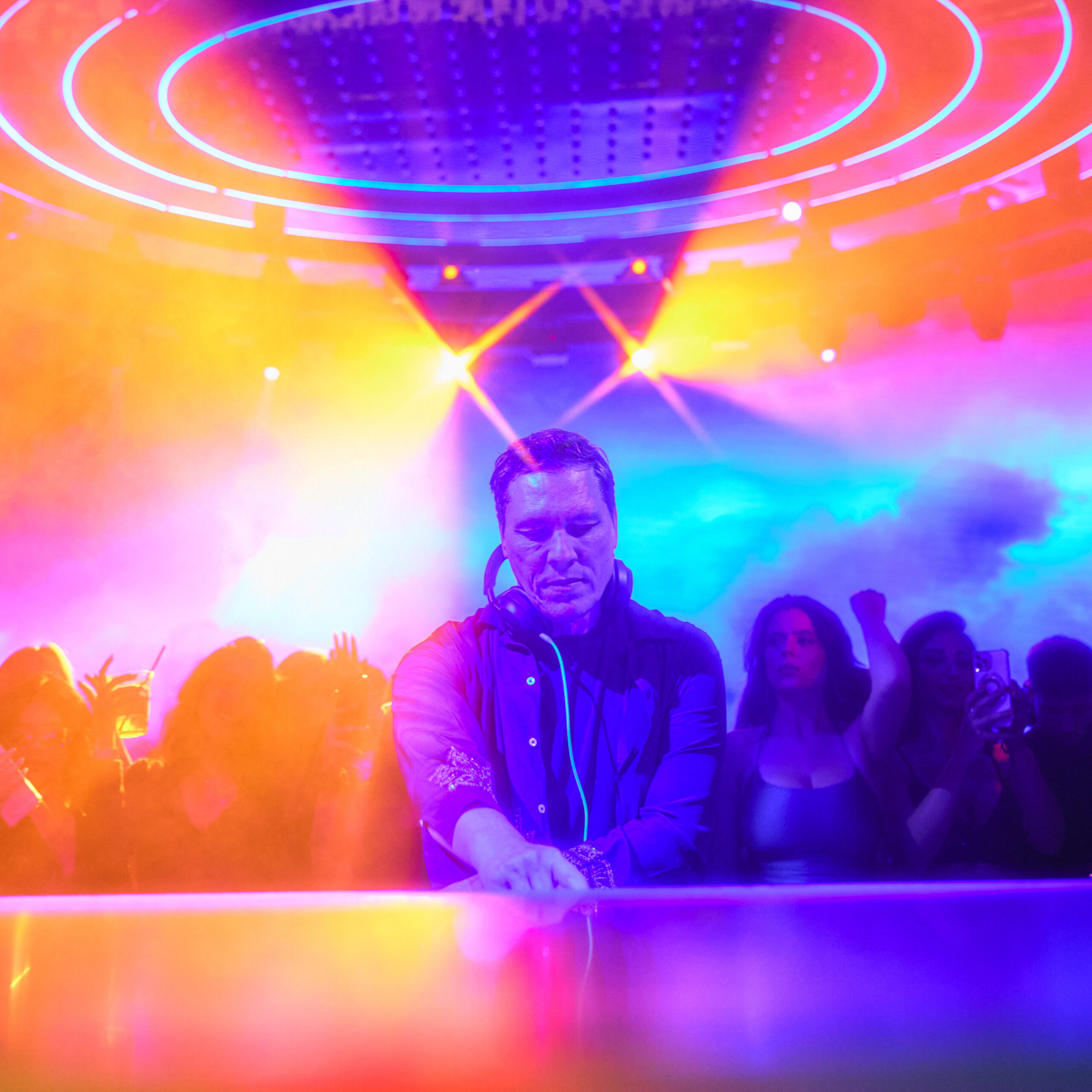 Tiësto performing under the iconic Halo at LIV Las Vegas, surrounded by immersive neon lighting and a packed dancefloor.