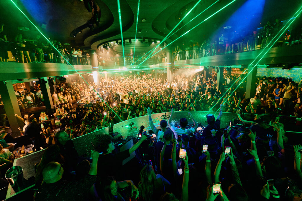 A packed, energetic crowd at LIV Las Vegas surrounded by laser lights.