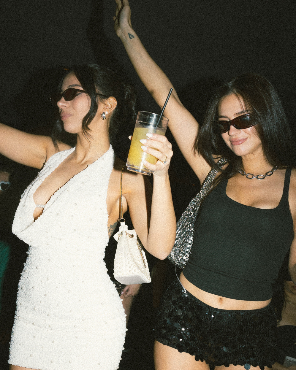Two girls dancing and wearing sunglasses.